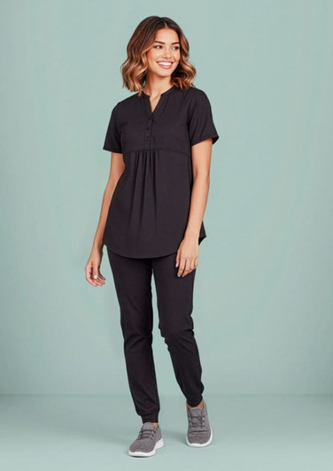 A black women's tunic scrub top is worn with matching pants, featuring a relaxed fit and button detail.