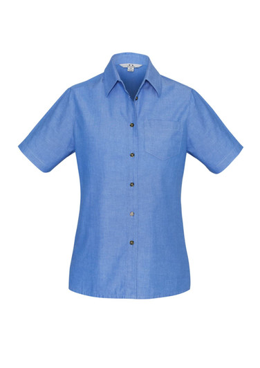 A women's short sleeve button-up shirt in light blue chambray fabric, featuring a single chest pocket and a branded logo.
