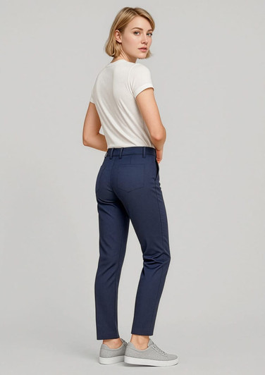 A woman stands wearing navy slim leg stretch chino pants and a white top, paired with grey sneakers.