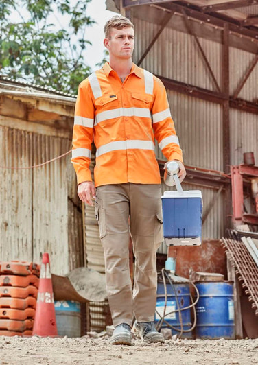 A man wears an orange long sleeve work shirt with reflective stripes, carrying a blue cooler in an outdoor setting.