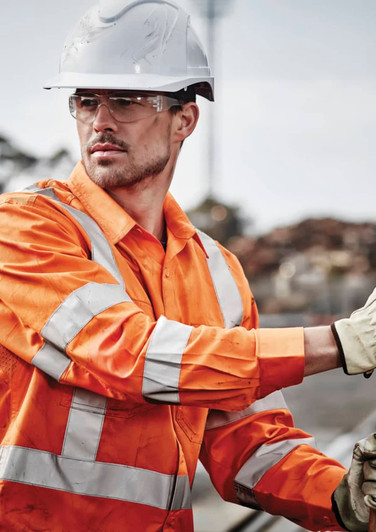 Hi-vis orange long sleeve work shirt with reflective tape, worn by a male worker in a construction setting, wearing safety gear.
