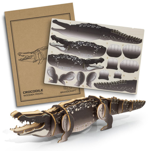 A wooden model crocodile in brown and grey, displayed next to its assembly instructions.