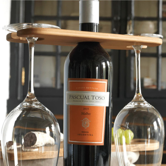 A wine bottle carrier with a bamboo top, holding a wine bottle and two glass stems. The glasses are clear and elegant.