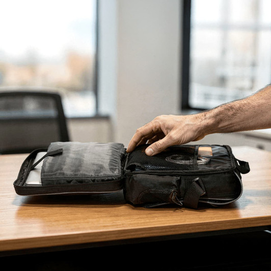A black laptop bag with various compartments, open to reveal an organiser and space for accessories.