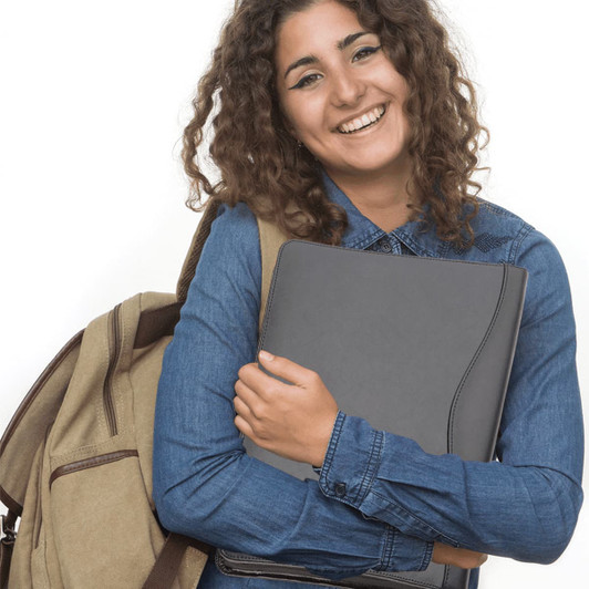 A woman with curly hair is smiling while holding a grey leather compendium. She wears a denim shirt and has a backpack.
