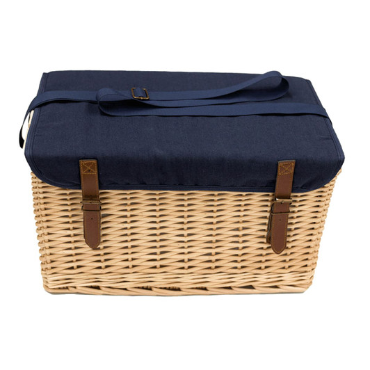 A wicker picnic basket in natural colour with a navy blue lid and leather straps. Features a carrying strap.