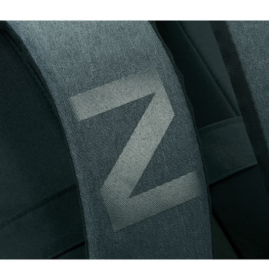 A close-up of the padded strap of a dark green laptop backpack featuring a simple logo.