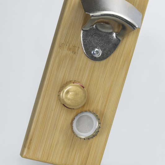 A drink bottle opener made of bamboo featuring a metallic bottle cap opener and two bottle caps.