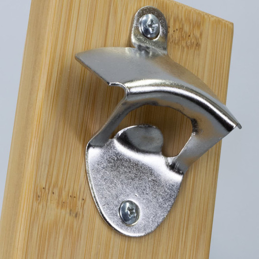 A drink bottle opener with a stainless steel finish mounted on a bamboo backboard. Features a small logo.