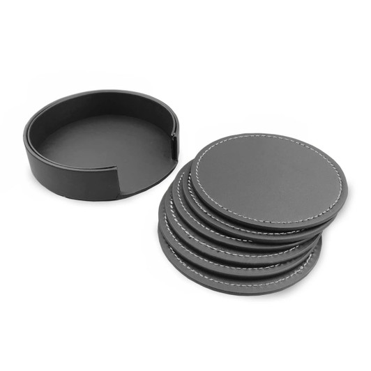 A set of six black leather coasters with white stitching, neatly arranged beside their round storage holder.