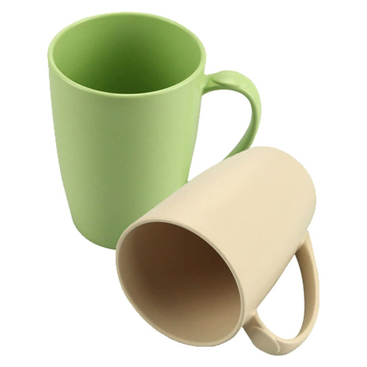 A bamboo mug set in green and beige, featuring a simple design and ergonomic handles. Includes a logo on one mug.