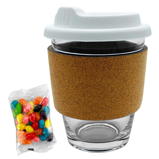 A glass coffee cup with a white lid and cork band, alongside a packet of colourful jelly beans.