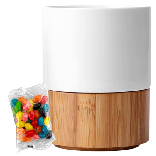 A white ceramic mug with a bamboo base alongside a packet of colourful jelly beans.