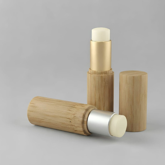 Bamboo lip balm sticks in bamboo tubes, featuring silver and gold caps, against a grey background.