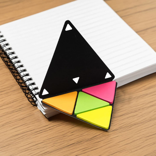 A triangular sticky note holder with black, pink, yellow, and green notes sits on a notepad with a spiral binding.