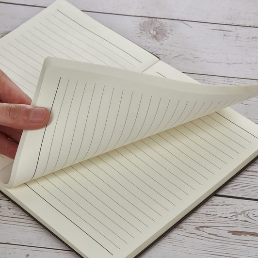 A5 wood-look notebook with lined pages, featuring a hand turning the pages, set on a wooden surface.