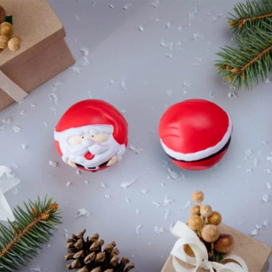 Two red stress toys shaped like Santa Claus heads, surrounded by festive decorations and snow-like confetti.