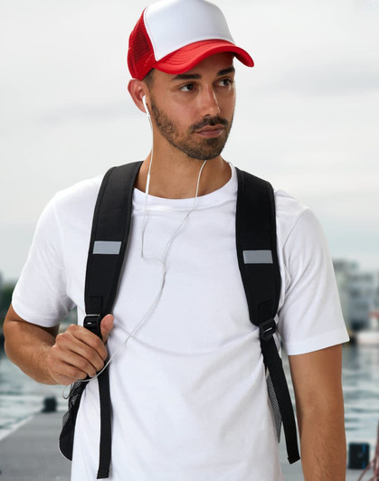 A black backpack worn by a man in a white t-shirt and a red and white cap, with earbuds visible.