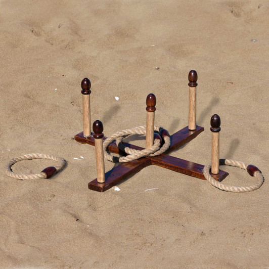 A wooden backyard quoits set on sandy ground, featuring several pegs and rope rings. It has a natural wood finish.