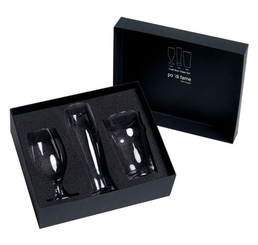 A black box containing three craft beer glasses in various shapes, resting on a soft black insert.