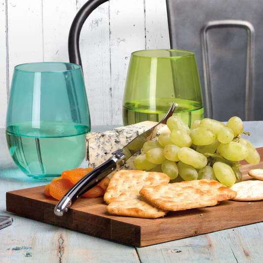 A cheese knife with a black handle rests on a wooden board with crackers, grapes, and blue cheese, accompanied by green glasses.