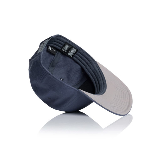 A navy cap with a grey brim, featuring an inner label and a logo. The cap is positioned at an angle.