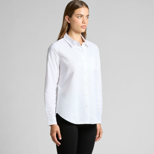A button-up shirt in white, featuring a single chest pocket and long sleeves. The model stands against a neutral background.