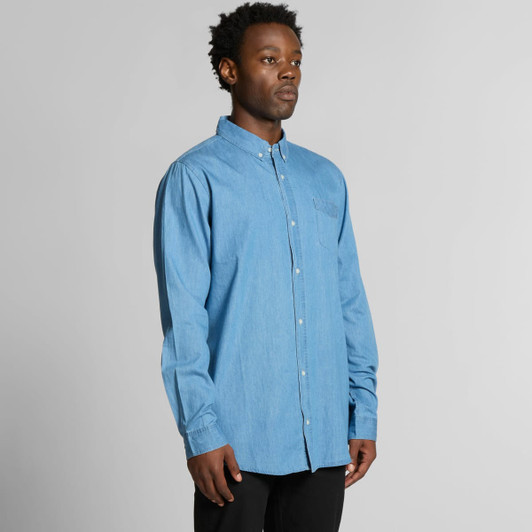 A blue denim button-up shirt with a pocket, featuring long sleeves and a collar. The shirt has a logo on it.