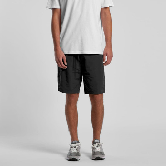 Black sports shorts featuring an elastic waistband and a logo, displayed with a plain white t-shirt and grey trainers.