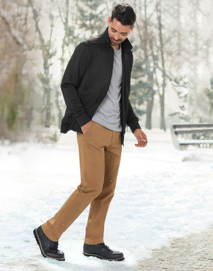 A man wearing a black jacquard fleece jacket, grey shirt, and tan pants, walking in a snowy outdoor setting.