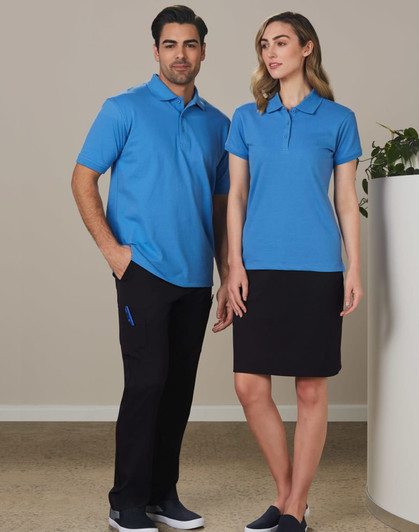 A man and woman standing together, wearing matching blue polo shirts. The man pairs his top with black cargo pants, while the woman wears a black skirt.