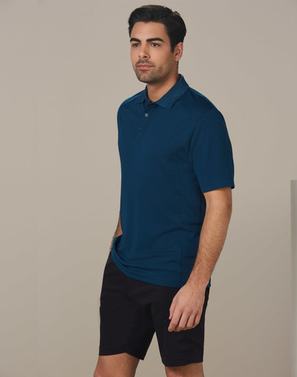 A man wearing a dark teal polo shirt and black cargo shorts, standing against a plain background.