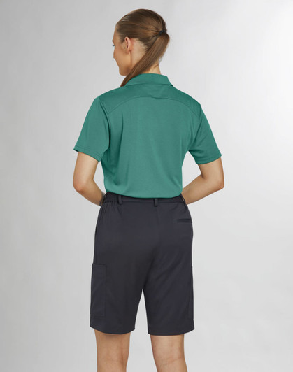 A woman in a green polo shirt and black utility cargo shorts, viewed from the back. The shorts have pockets and are knee-length.