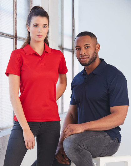 A red women's polo shirt and a navy blue men's polo shirt displayed on models in a bright, modern setting.