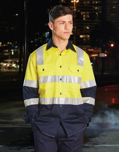 A safety shirt in bright yellow with navy blue sleeves and reflective tape, displayed on a model at night.