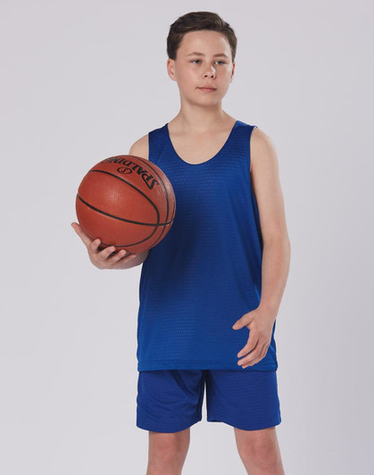 A boy wearing a blue basketball singlet and shorts, holding a basketball, with a simple background.