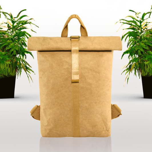 A tan kraft paper backpack with a roll-top closure and adjustable straps, surrounded by potted plants.