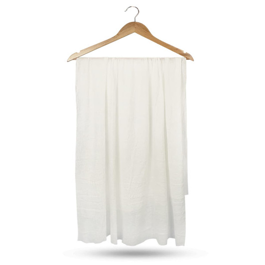 A white compressed towel hanging on a wooden hanger, featuring a textured surface and a simple design.