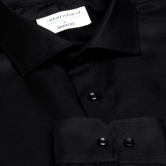 A close-up of a black button-up shirt featuring a collar and glossy buttons. The shirt has a logo label.