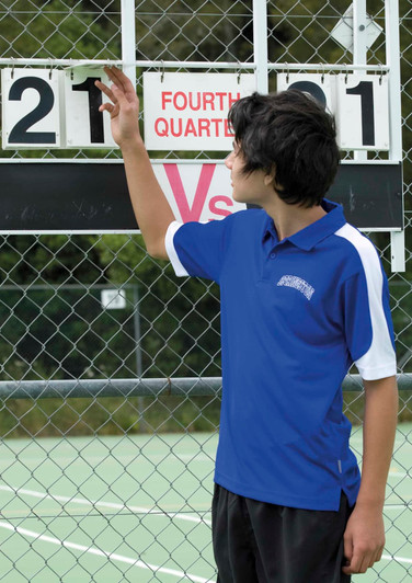 A young person adjusts a scoreboard while wearing a blue and white polo shirt with a logo.