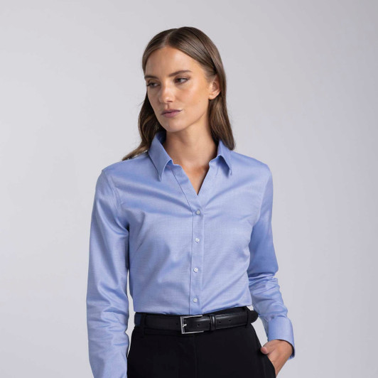 A light blue women's button-up shirt with a collar and long sleeves, featuring a logo.