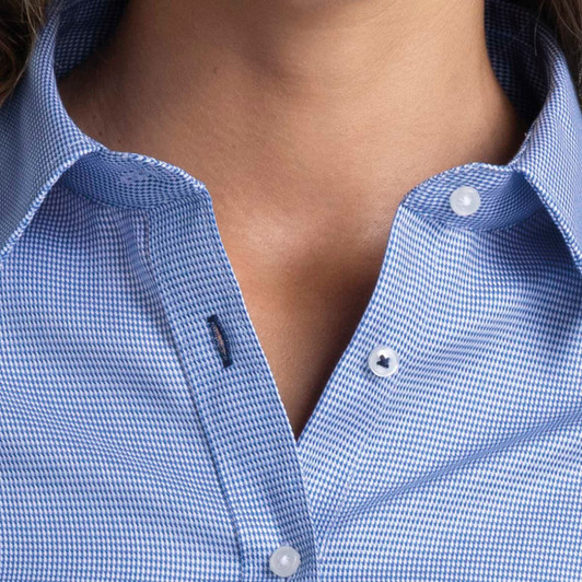 A close-up of a women's button-up shirt in blue with a checkered pattern, featuring a collar and buttons.