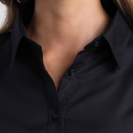 A close-up of a women's button-up shirt in black featuring a collar and button detailing.