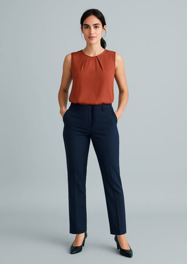 A model wearing navy tapered leg pants and a rust-coloured sleeveless top, with hands in pockets.