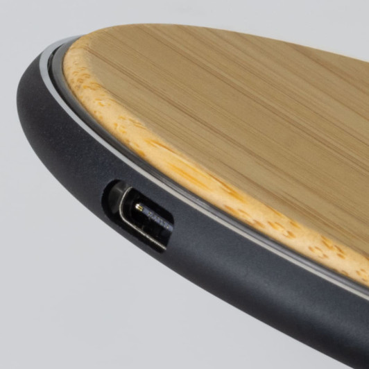 A bamboo wireless fast charger featuring a sleek black edge and a USB port.