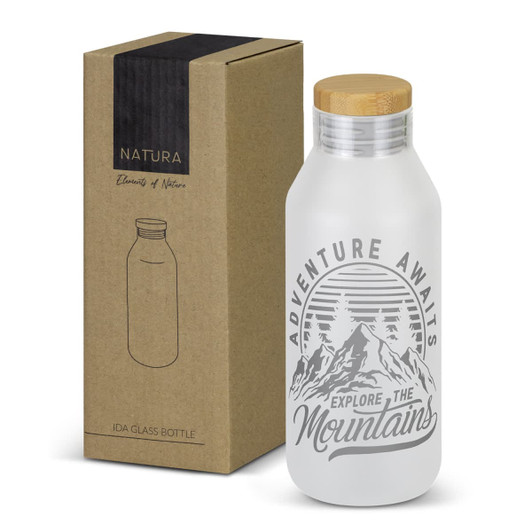 A drink bottle with a frosted glass finish, wooden lid, and mountain-themed design, accompanied by a cardboard box.
