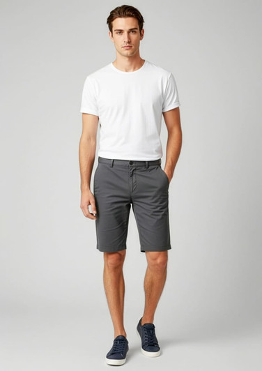 A model wearing grey dress shorts paired with a white t-shirt and navy shoes, featuring a branding logo.