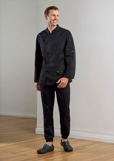 A man wearing black chef uniform, featuring a double-breasted jacket and jogger pants, with black clogs on his feet.
