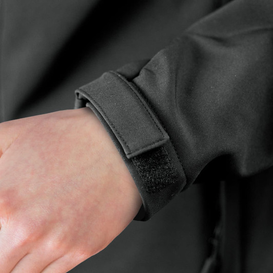 A close-up of a black soft shell jacket cuff with a Velcro strap. The fabric appears smooth and sleek.
