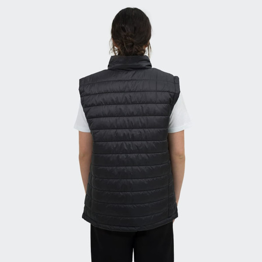 A women's puffer vest in black, featuring a high collar and a quilted design, worn over a white top.
